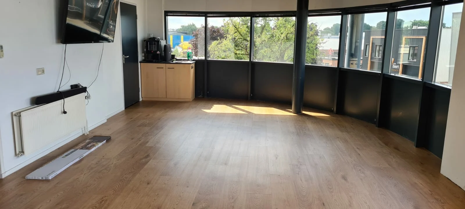 Ruime kamer met een houtlook PVC-vloer en een rij ramen