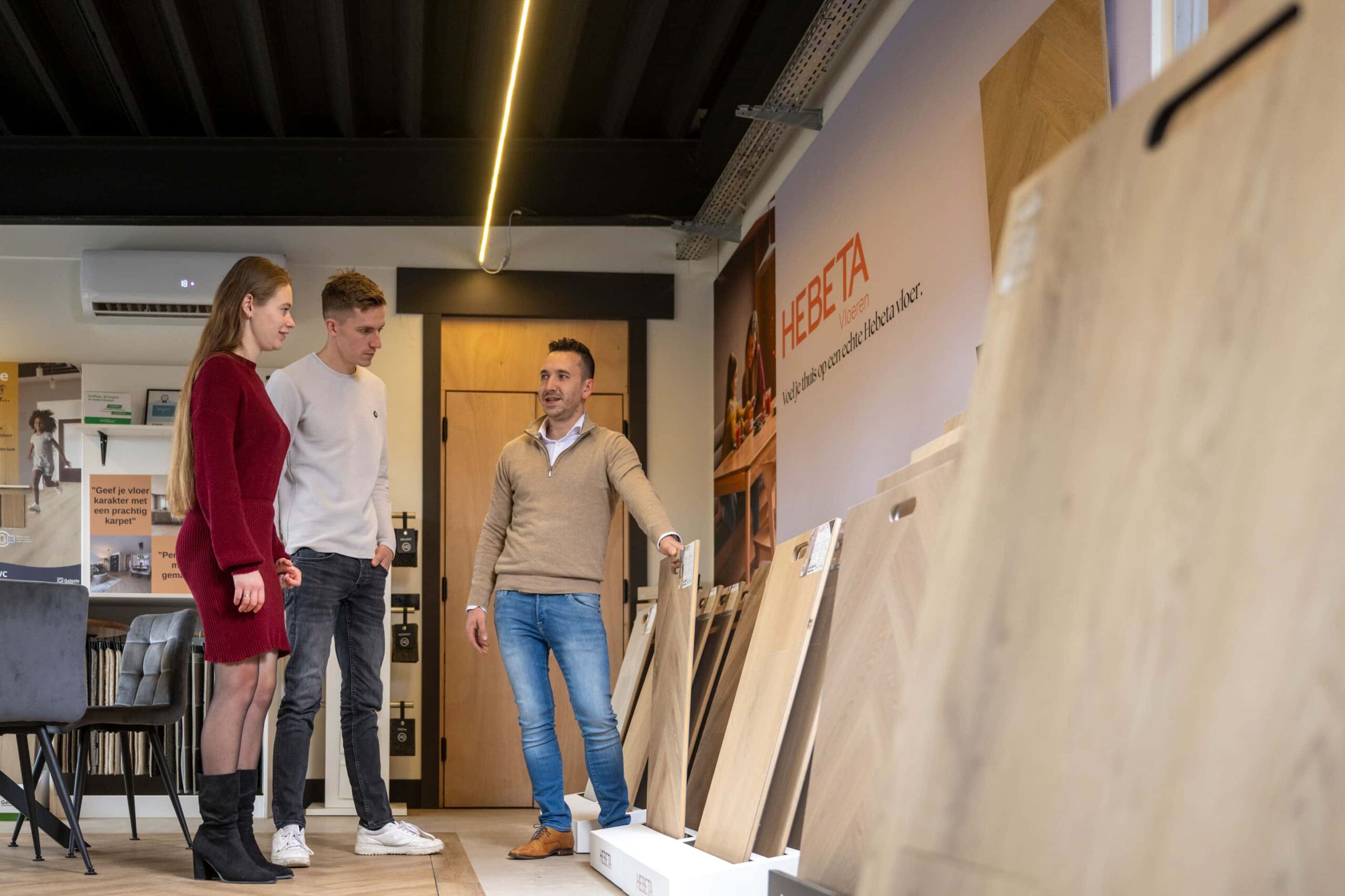Adviseur van Blankers Vloeren toont vloerdelen aan een stel in de showroom