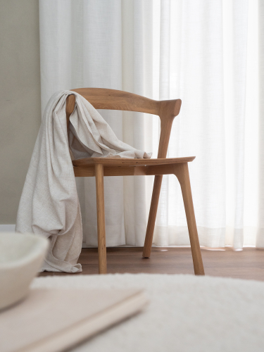 Lichte vitrage voor een raam met een houten stoel