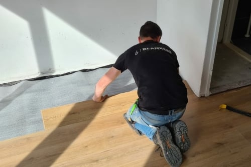 Vakman legt een click PVC-vloer op een ondervloer