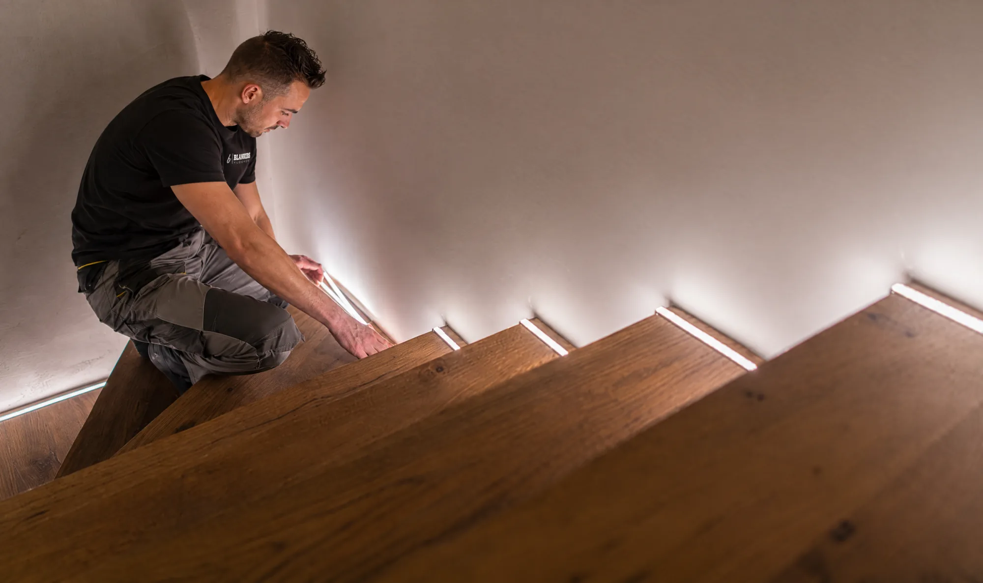 Impressie van een vakman van Blankers die ledverlichting aanbrengt onder de traptreden