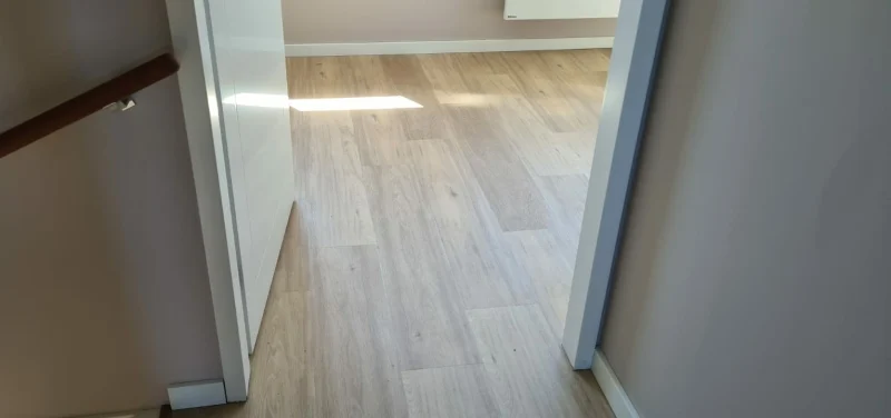Lichte PVC-vloer in stroken in een slaapkamer, gezien vanaf de overloop