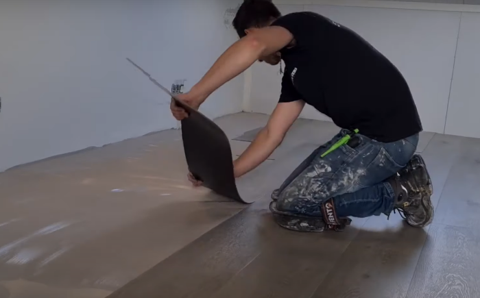 Vakman legt PVC-vloerdelen op een vlakke ondergrond
